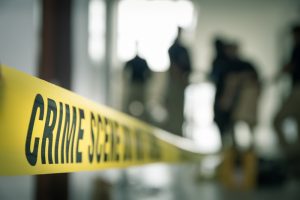 Hipnose forense: faixa amarela escrito "CRIME SCENE", e pessoas desfocadas no fundo de uma sala.